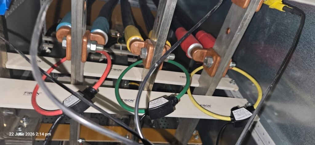 Rogowski coil current transducers clamped around copper busbars inside a distribution panel and connected to a power logger