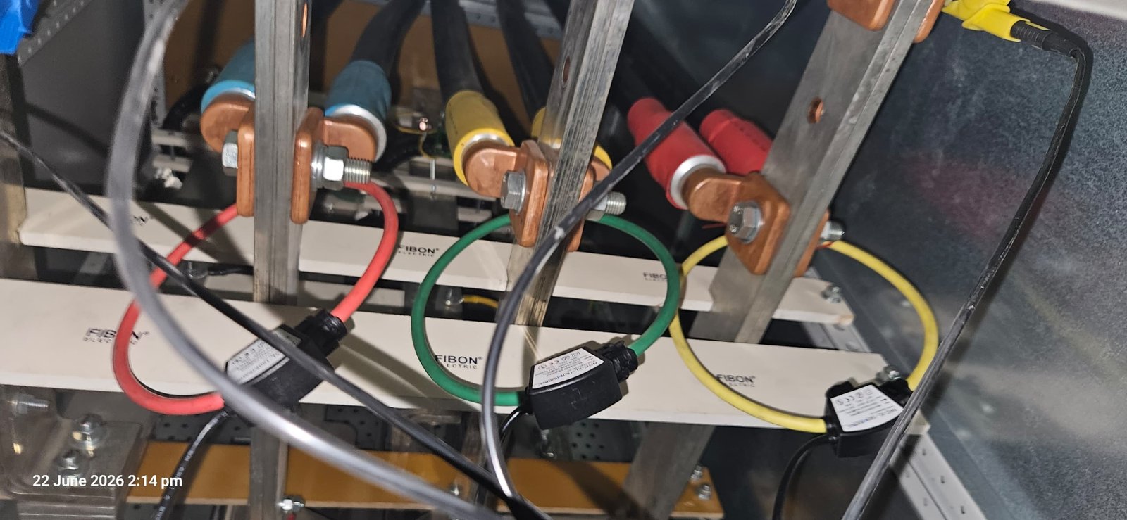 Rogowski coil current transducers clamped around copper busbars inside a distribution panel and connected to a power logger